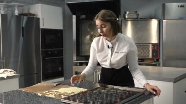 Genç aşçı kız tatlı yapıyor. Tatlı ve kek pişirir. Boşlukları doldurur ve meyveleri hazırlar. Pişirme, tatlı, tatlılar, karmaşık pişirme süreçleri.