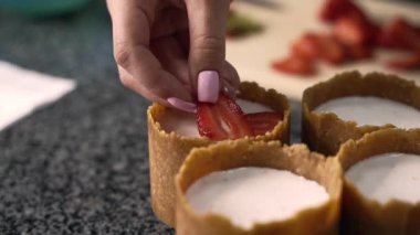 Genç aşçı kız tatlı yapıyor. Tatlı ve kek pişirir. Boşlukları doldurur ve meyveleri hazırlar. Pişirme, tatlı, tatlılar, karmaşık pişirme süreçleri.