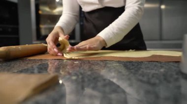 Genç aşçı kız tatlı yapıyor. Tatlı ve kek pişirir. Boşlukları doldurur ve meyveleri hazırlar. Pişirme, tatlı, tatlılar, karmaşık pişirme süreçleri.