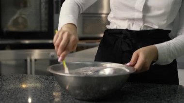 Genç aşçı kız tatlı yapıyor. Tatlı ve kek pişirir. Boşlukları doldurur ve meyveleri hazırlar. Pişirme, tatlı, tatlılar, karmaşık pişirme süreçleri.