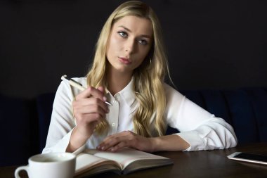 Female student writing organisation plan in textbook for education using pen for making notes, image of womans processing information for university course work in knowledge notepad on coffee break.