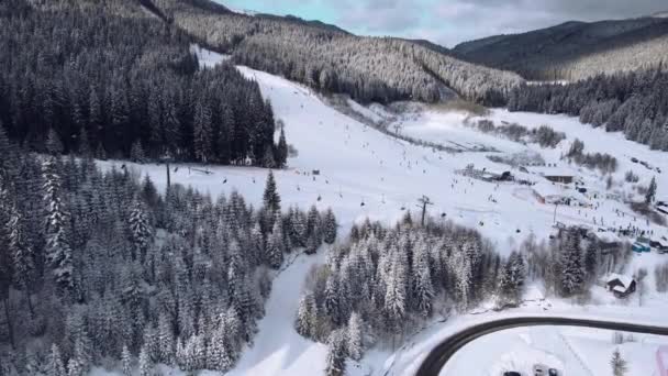 Ukraina, Bukowel, 16 stycznia 2022 r.: Widok z lotu ptaka na ośrodek narciarski z narciarzami w dół wzgórza i w górę wyciągu — Wideo stockowe