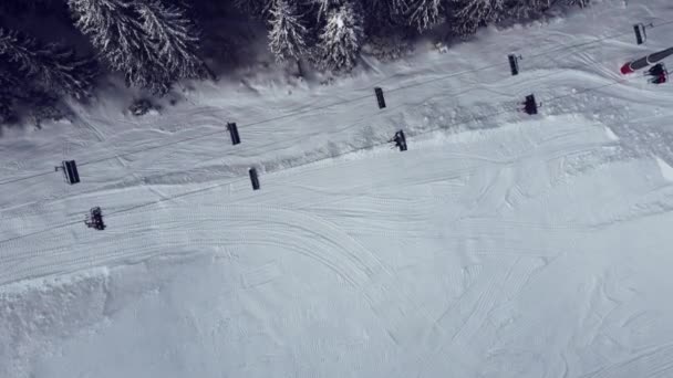 Вид с воздуха на горнолыжный курорт с людьми, катающимися на лыжах с холма и подъемника — стоковое видео