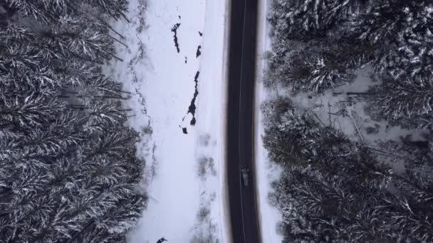 Воздушный вид на заснеженные лесные горы с легковыми автомобилями на зимней дороге. — стоковое видео