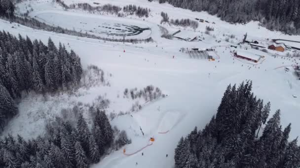 Bukowel, Ukraina - 16 stycznia 2022: Widok z lotu ptaka na ośrodek narciarski z narciarzami w dół wzgórza i w górę wyciągu — Wideo stockowe