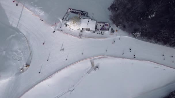 人々とスキーリゾートの空中ビューは 丘を下り リフトを上ります 冬のスキー休暇の映像 自然景観4Kビデオ — ストック動画