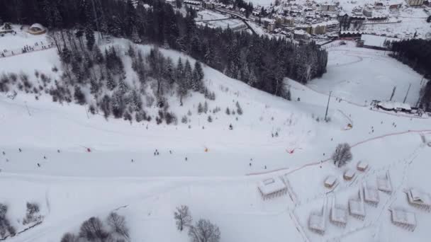 Буковель, Украина - 16 января 2022 года: Вид с воздуха на горнолыжный курорт с катанием на лыжах с холма и подъемника — стоковое видео