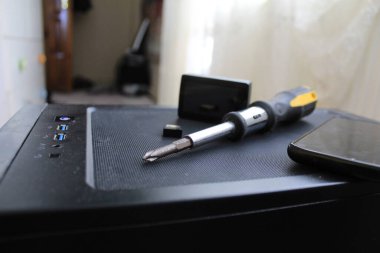 A USB memory stick, screwdriver, and an action camera on a computer case. Black concept. High quality photo