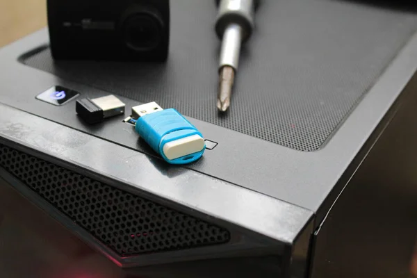 A USB memory stick, screwdriver, and an action camera on a computer case. Black concept. High quality photo