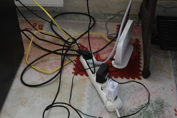 Cable mess on a carpet with some plugged sockets. High quality photo