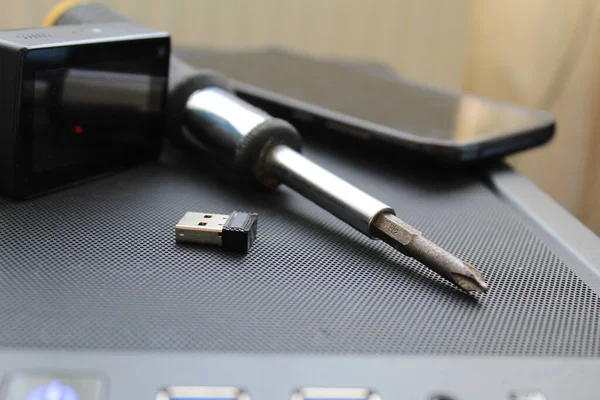 A USB memory stick, screwdriver, and an action camera on a computer case. Black concept. High quality photo