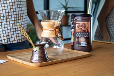 A woman preparing a bottle of coffee on a wooden desk. Reusable coffee filter. High quality photo