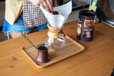A woman preparing a bottle of coffee on a wooden desk. Reusable coffee filter. High quality photo