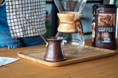 A woman preparing a bottle of coffee on a wooden desk. Reusable coffee filter. High quality photo