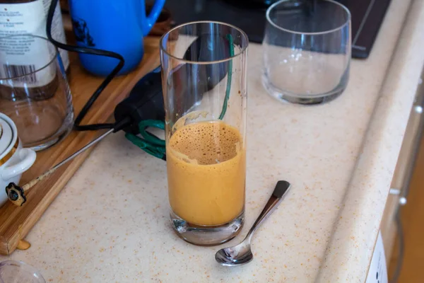 A woman hand preparing a glass of cold coffee on a wooden cutting board at kitchen. High quality photo