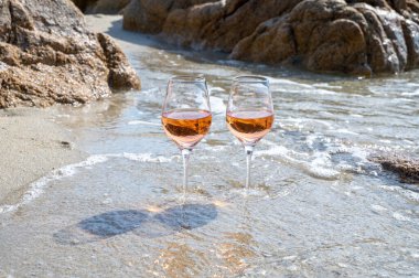 Provence 'de yaz mevsimi, güneşli bir günde Saint-Tropez yakınlarındaki kumlu sahilde iki bardak soğuk gül şarabı, Var Bölümü, Fransa