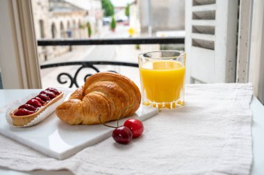Fransız kahvaltısı, taze kruvasan tereyağlı pasta arkaplanda lezzetli portakal suyu ve eski Fransız evleriyle servis ediliyor.