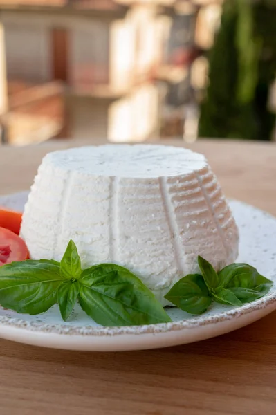 チーズコレクション 白イタリアのソフトチーズリコッタに新鮮なトマトとバジルを添えて屋外で提供しています背景にイタリアの家 — ストック写真