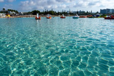 Kıbrıs Rum Kesimi 'nin Ayia Napa kentindeki beyaz kumlu Nissi plajında Akdeniz' in berrak mavi suyu