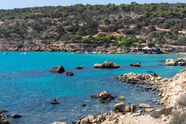 Akdeniz 'in berrak mavi suyu ve Kıbrıs Rum Kesimi' nin Protaras yakınlarındaki kumlu Konnos plajında sarı kayalar