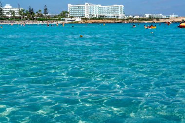 Kıbrıs Rum Kesimi 'nin Ayia Napa kentindeki beyaz kumlu Nissi plajında Akdeniz' in berrak mavi suyu