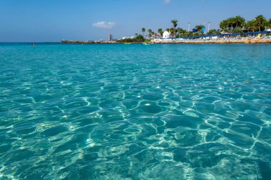 Kıbrıs Rum Kesimi 'nin Ayia Napa kentindeki beyaz kumlu Nissi plajında Akdeniz' in berrak mavi suyu