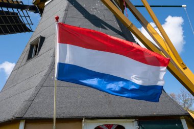 Hollanda bayrağı ve arka planda tahıl öğütmek için kullanılan eski geleneksel yel değirmeni