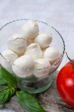 Kırmızı domates ve taze yeşil fesleğenle servis edilen taze, yumuşak mozzarella topları.