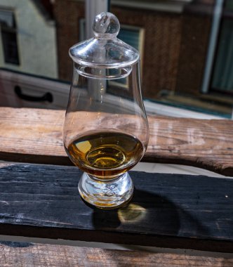 Tek malt viski bardağında servis edilen viski bardağı, eski pencerenin manzarası ve kullanılmış ahşap kutunun üzerindeki evler.
