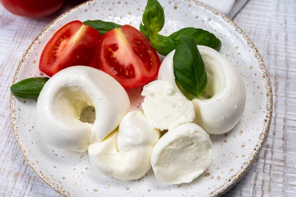 Güney İtalyan yumuşak beyaz mozzarella peyniri bufalo ineklerinden yapılmış taze domates ve taze yeşil fesleğenle servis edilen süt yakın mesafede.