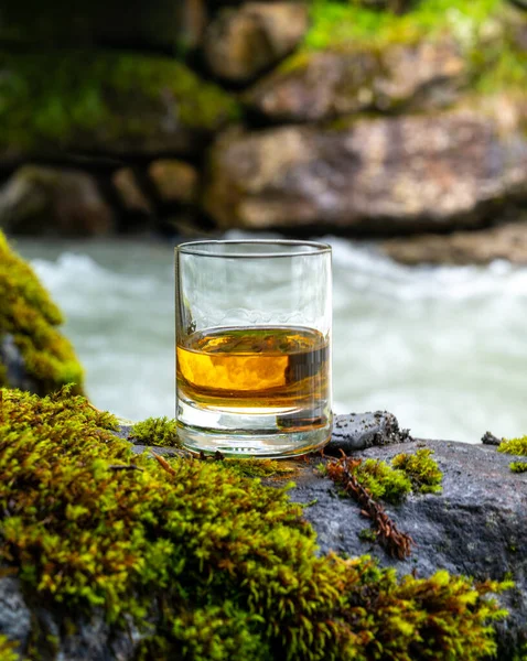 苏格兰 苏格兰 一杯浓郁的苏格兰单麦芽威士忌 背景是快速流淌的山河 — 图库照片