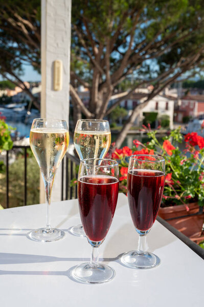 Summer party with kir royal cocktail, tasting of French brut champagne sparkling wine and cold creme cassis in glasses in yacht harbour of Port Grimaud near Saint-Tropez, French Riviera vacation, France