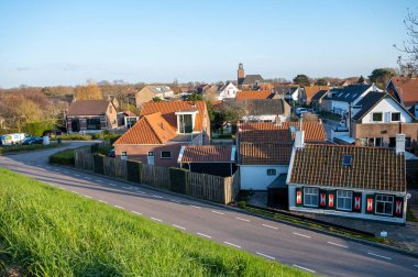 Scharendijke 'de yürürken, Hollanda' nın Zealand şehrinde eski evleri ve Grevelingenmeer 'in mavi sularıyla küçük bir kasaba manzarası var.