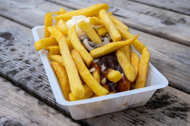 Köri ve mayonez soslu patates cipsi ve ahşap masada soğan.