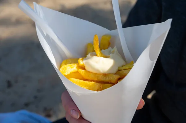 Eating of street or take away food fresh baked french fried potatoes chips in paper cone