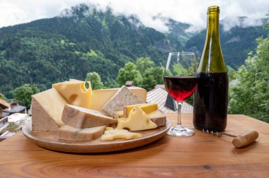 Peynir koleksiyonu, Fransız peynirli ahşap pano kont, Beaufort, abondance, emmental, morbier, Savoie 'den kırmızı şarap ve yazın Haute-Savoie' deki Fransız dağları köyünden gelen kırmızı şarap.