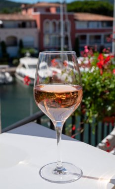 Fransız Riviera Cote d 'Azur' da yaz mevsimi, Cotes de Provence 'den soğuk gül şarabı içmek Port Grimaud, Var, Fransa' da güneşli açık teraslarda arka planda botlar ve yatlarla