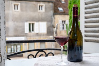 Burgundy şarap bölgesindeki Grand Cru Pinot üzüm bağlarından şarap, cam ve bir şişe kırmızı şarap ve eski kasaba caddesinin görüntüsü Fransa 'nın Burgundy şarap bölgesinde