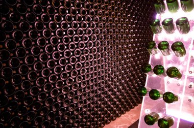 Derin ve uzun yeraltı mağaralarındaki raflarda şişeler şarap ve üzüm şarabından şampanya yapıyor Reims, Champagne, France 'ta.