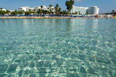 Kıbrıs Rum Kesimi 'nin Ayia Napa kentindeki beyaz kumlu Nissi plajında Akdeniz' in berrak mavi suyu