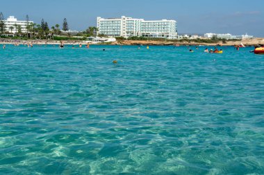 Kıbrıs Rum Kesimi 'nin Ayia Napa kentindeki beyaz kumlu Nissi plajında Akdeniz' in berrak mavi suyu