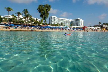 Kıbrıs Rum Kesimi 'nin Ayia Napa kentindeki beyaz kumlu Nissi plajında Akdeniz' in berrak mavi suyu