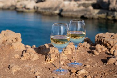 Kıbrıs 'taki Protaras turistik kasabası yakınlarındaki mavi deniz koyunda iki bardak beyaz şarap servis ediliyor.