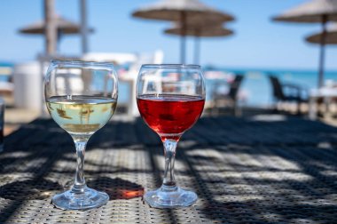 Soğuk gül ve beyaz şarap içmek güneşli kumlu sahildeki bar, arka planda mavi deniz suyu, yaz tatili