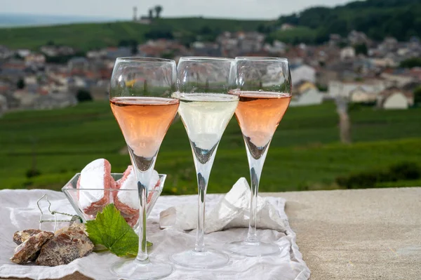 Glasses of white and rose brut champagne sparkling wine and examples of vineyard soils, white chalk stones and firestones and view on grand cru vineyards of  Montagne de Reims near Verzenay, Champagne, France