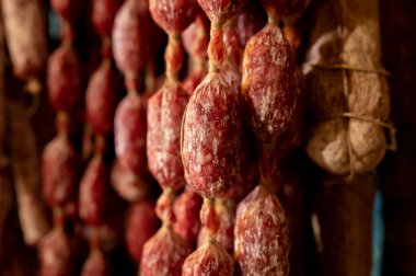 Parma, Emilia Romagna, İtalya 'daki kasapta asılı duran ev yapımı kurutulmuş salam sosisleri, et yemekleri arka planı.