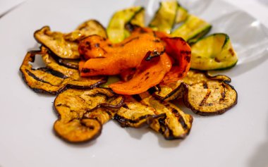 İtalyan mutfağı, rengarenk sebzeler kabak, patlıcan, beyaz tabakta baharatlı balkabağı.