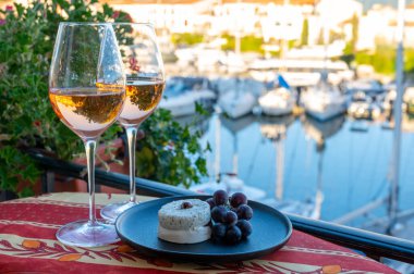 Yaz aylarında yerel gül şarabı ve yumuşak Fransız keçi peyniri tatmak ve arka planda Port Grimaud limanı, Provence, Var, Fransa
