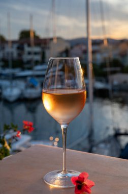 Yaz günbatımında yerel soğuk gül şarabının tadına bakmak arka planda liman, Provence, Var, Fransa