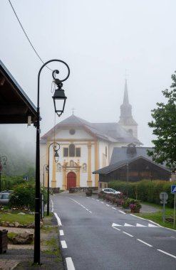Saint-Gervais-les-Bains yakınlarındaki sisli küçük bir köydeki dağ şapelinin manzarası, Savoy, Fransa
